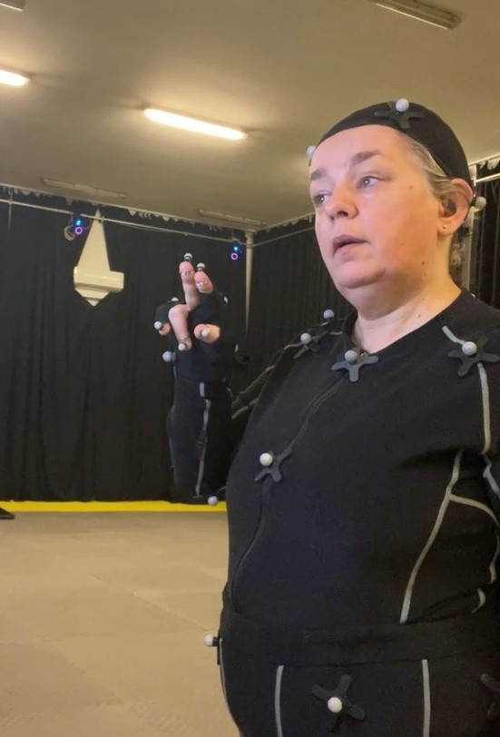 A performer in a motion capture suit with markers, in the SignaNova studio